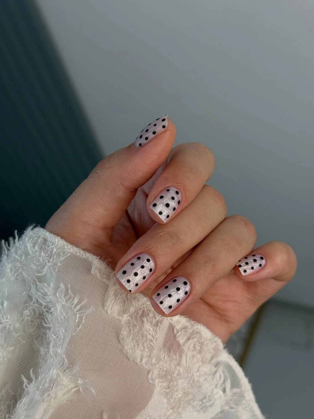 Pale pink nails with black geometric tips and tiny dots