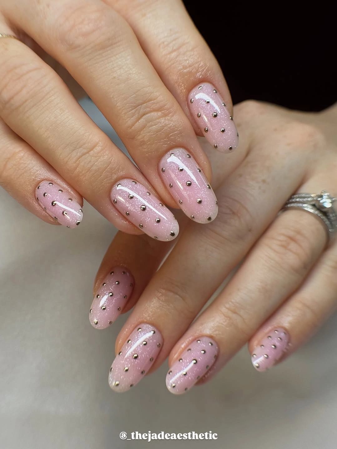 Pale pink almond nails with black dots and bead accents