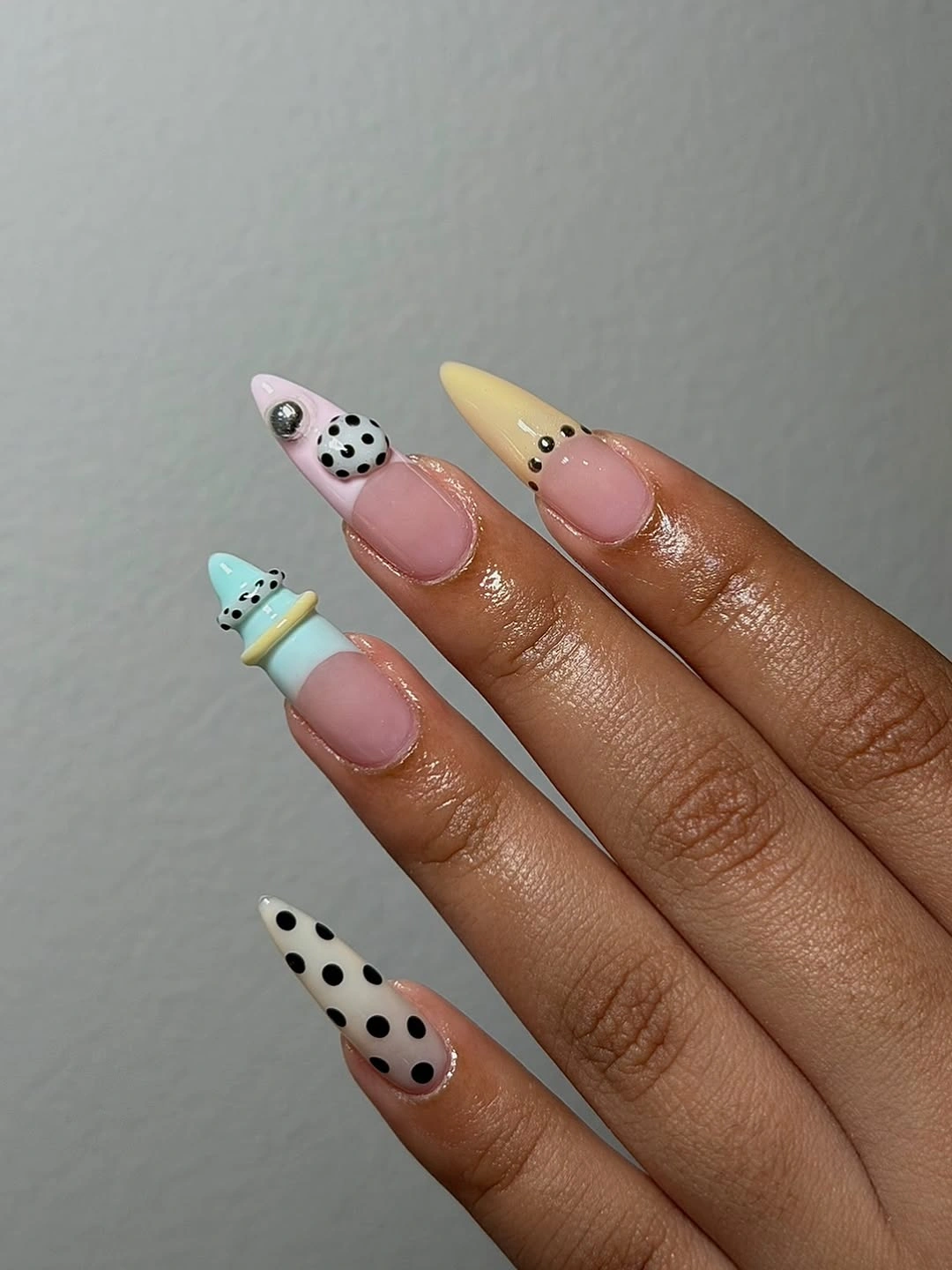 Long nude stiletto nails with pastel tips black dots and bow