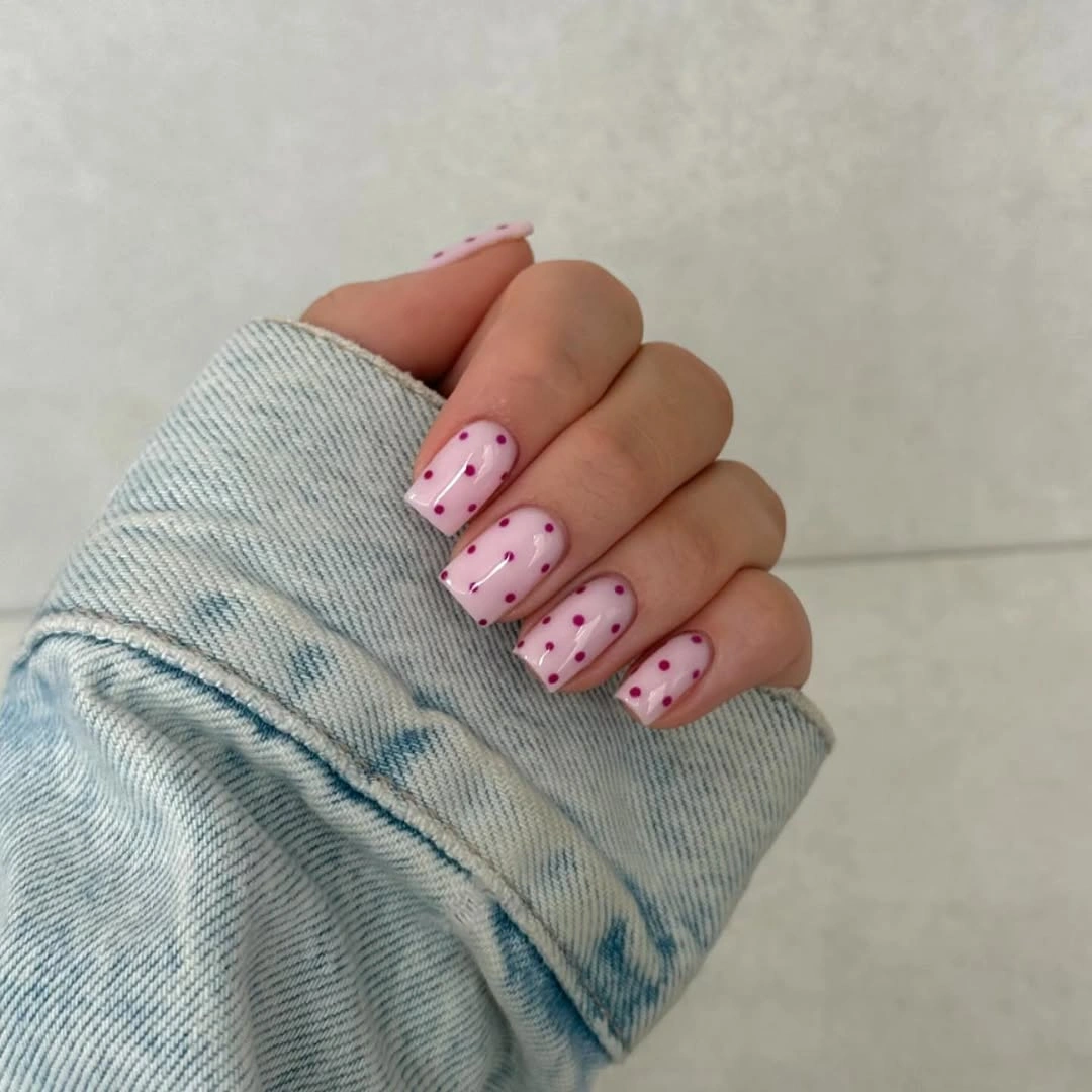 Soft pink square nails with tiny dark dots in vertical rows