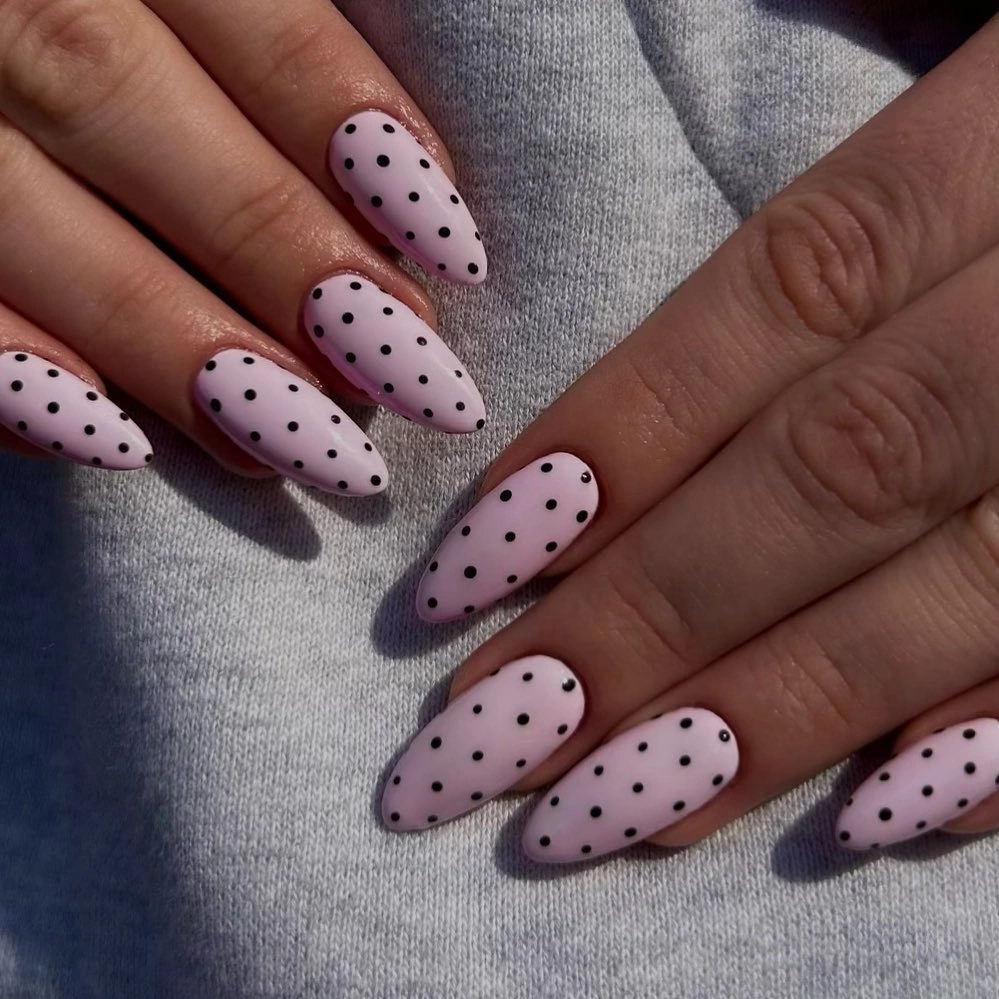 Medium pale pink almond nails with evenly distributed black dots