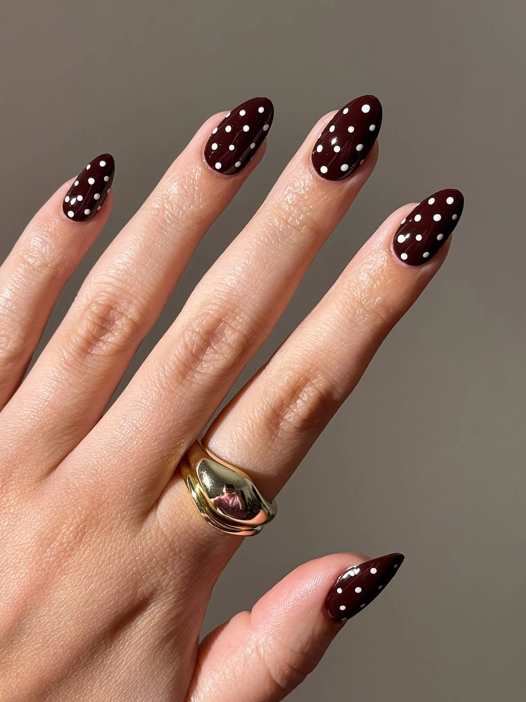 Deep burgundy almond nails with evenly spaced small white dots