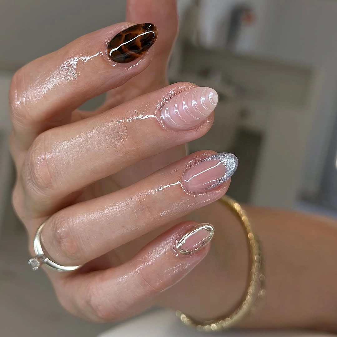 Short pearly pink nails with lilac swirls and dark accent