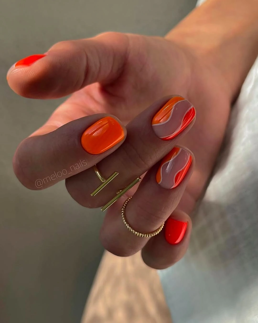 Short nude nails with orange and red curved bands