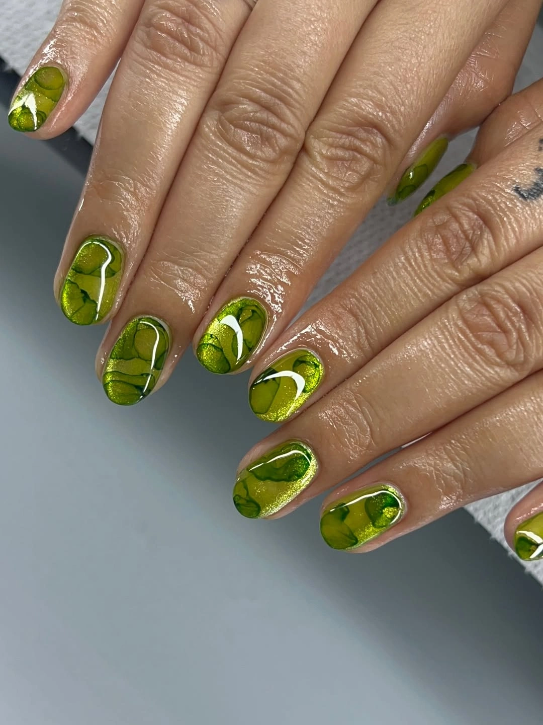 Short glossy olive nails with pale abstract swirls