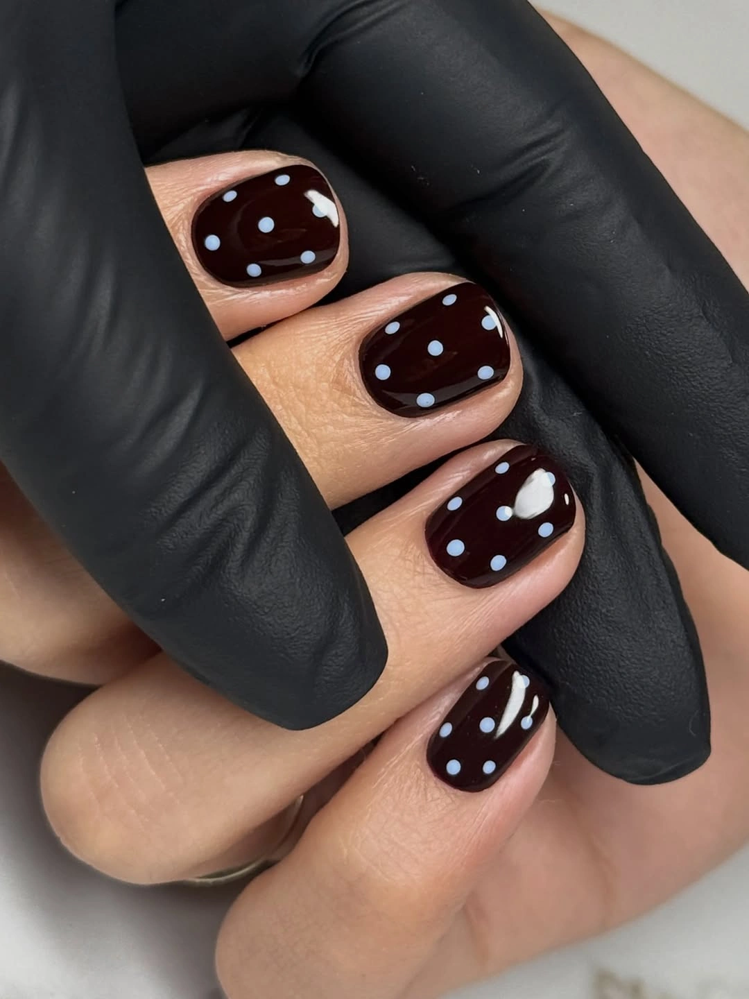 Short dark brown nails with pale blue white dots