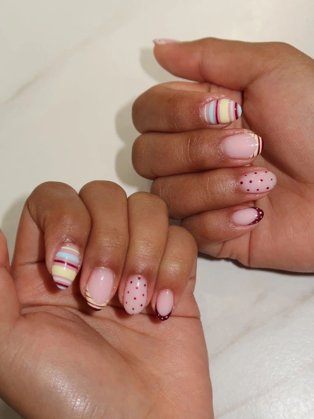 Short pale pink nails with striped and dotted accents