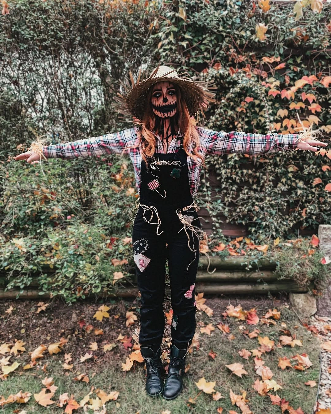 Skeleton-print top with dark floral overalls wide straw hat and black boots