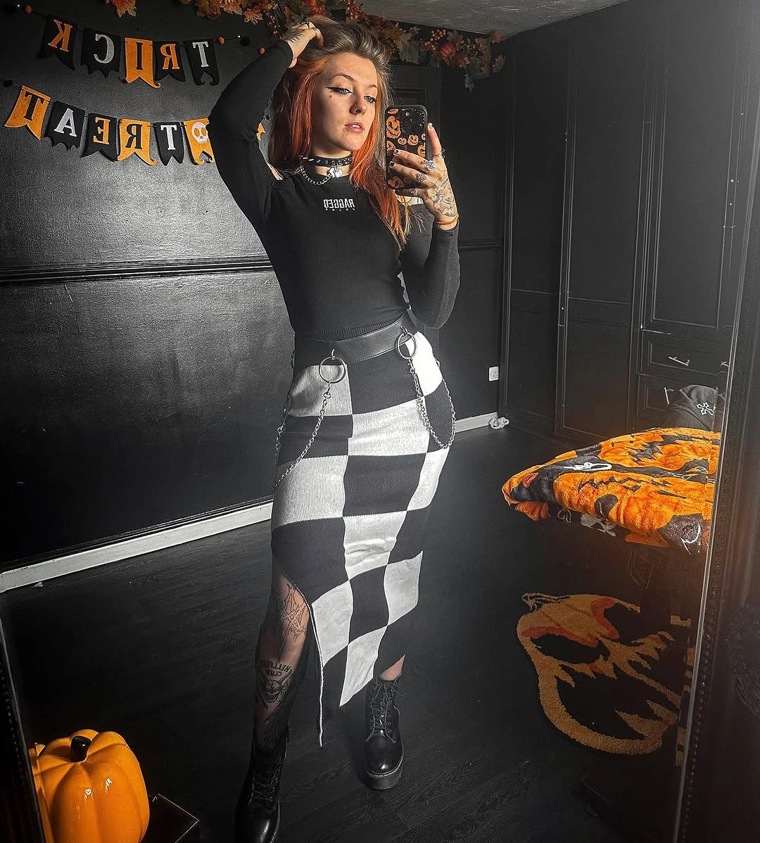 Black fitted top with high-contrast checkerboard trousers and dark boots for Halloween