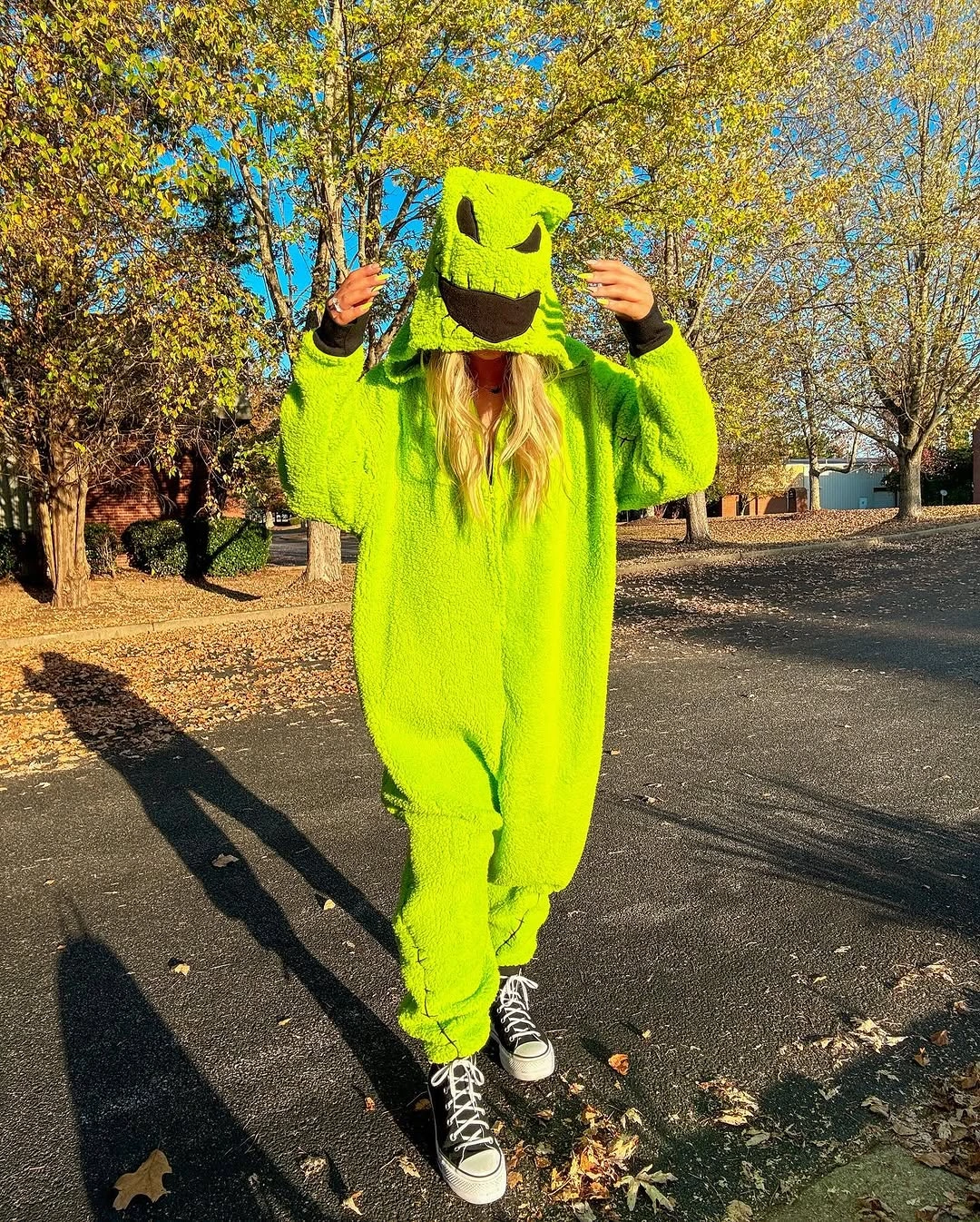 Bright green monster-style Halloween onesie with black-and-white sneakers outdoors