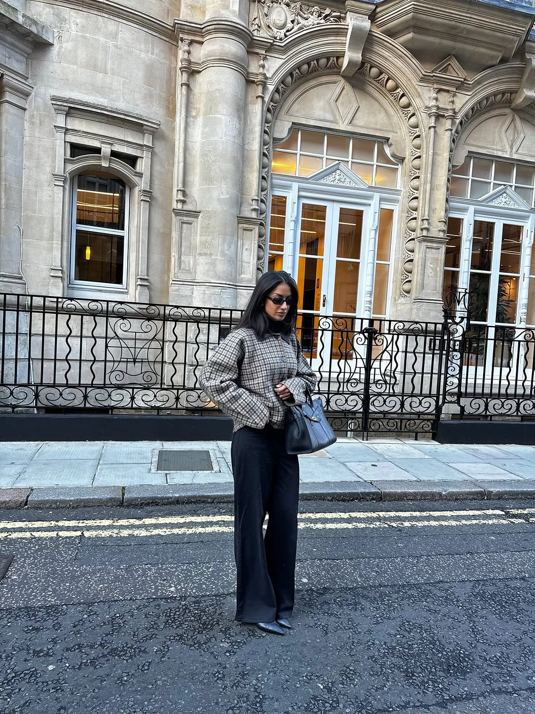 Gray textured jacket with black wide trousers and blue shoulder bag
