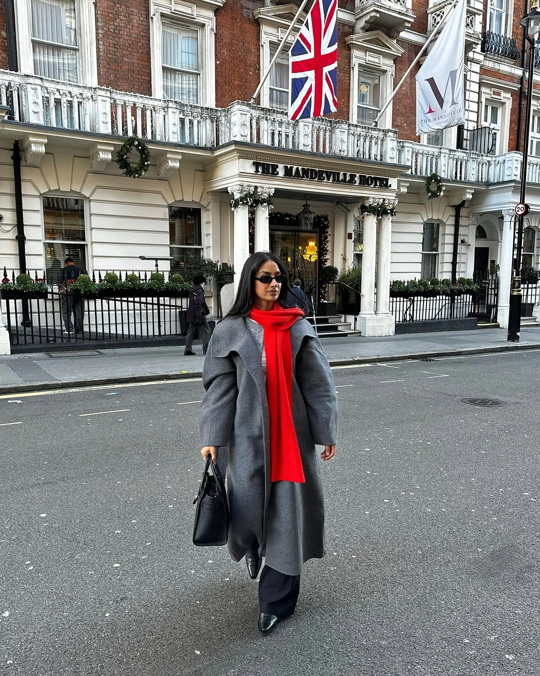 Gray coat with bright red scarf, black trousers, and black bag