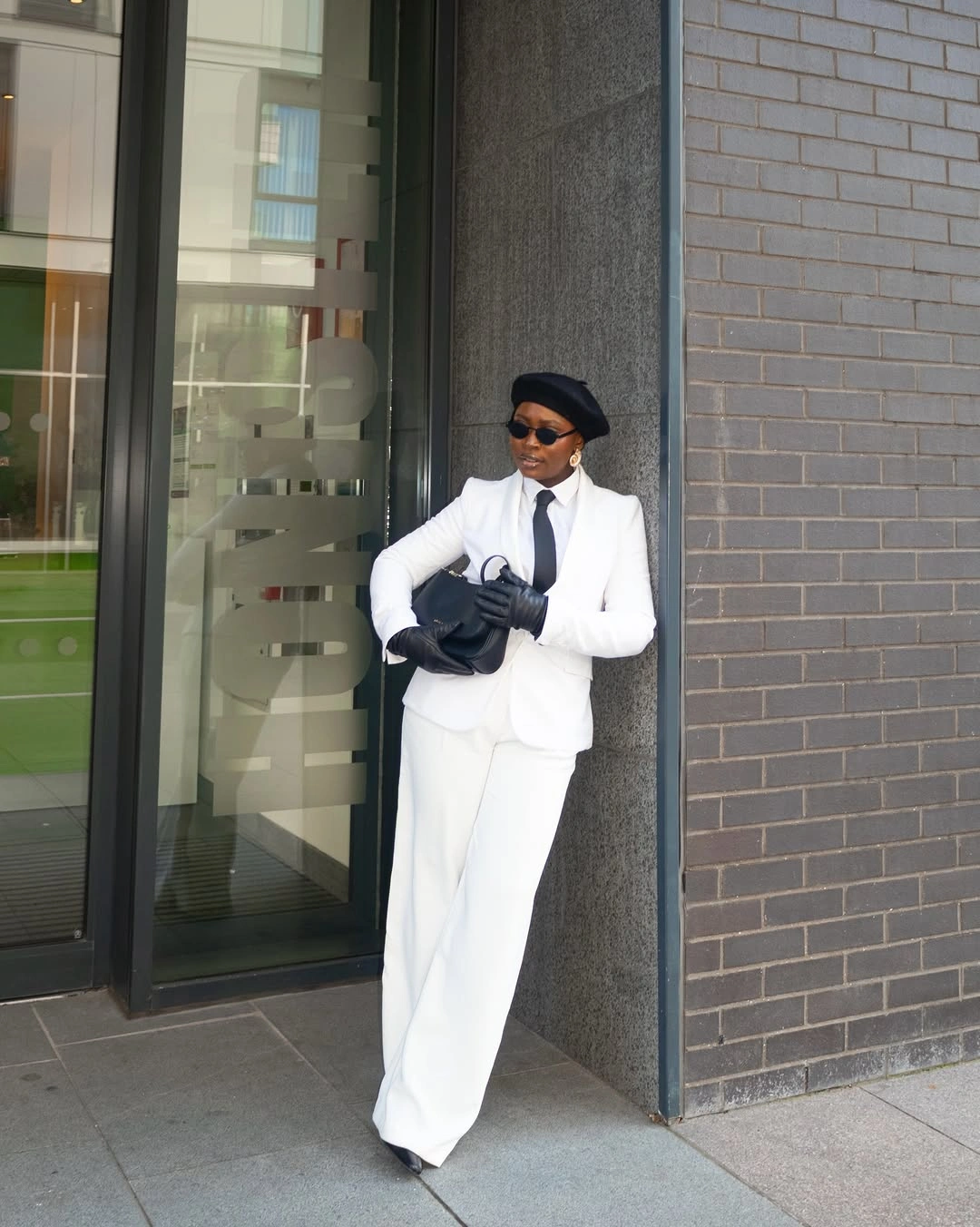 White tailored suit with black gloves, beret, and black bag