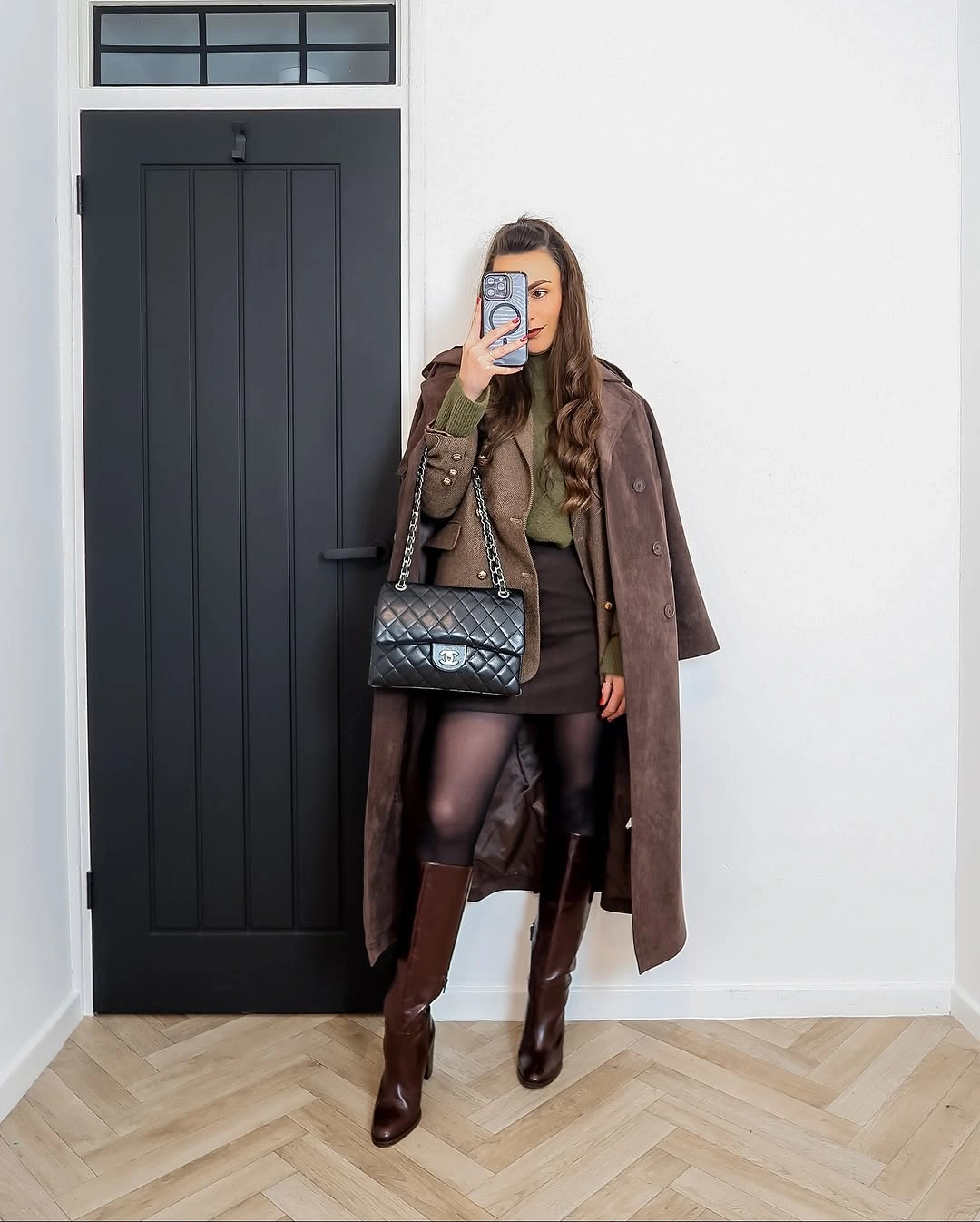 Brown long coat with dark short hem, tights, and tall brown boots
