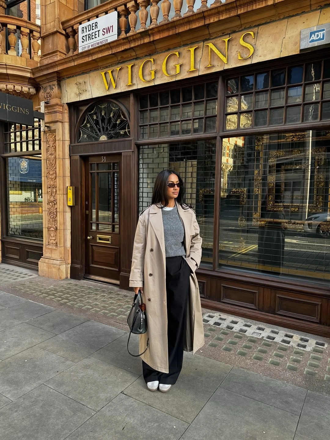 Cream long coat over black turtleneck and wide dark trousers