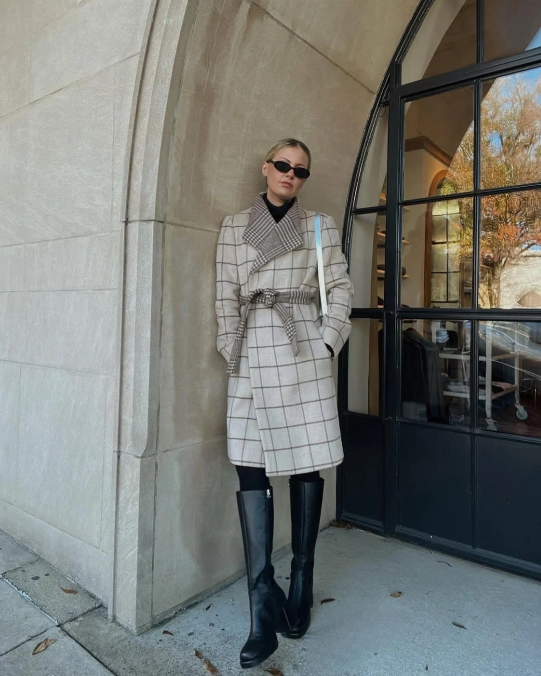 Checked belted coat with black turtleneck and tall black boots