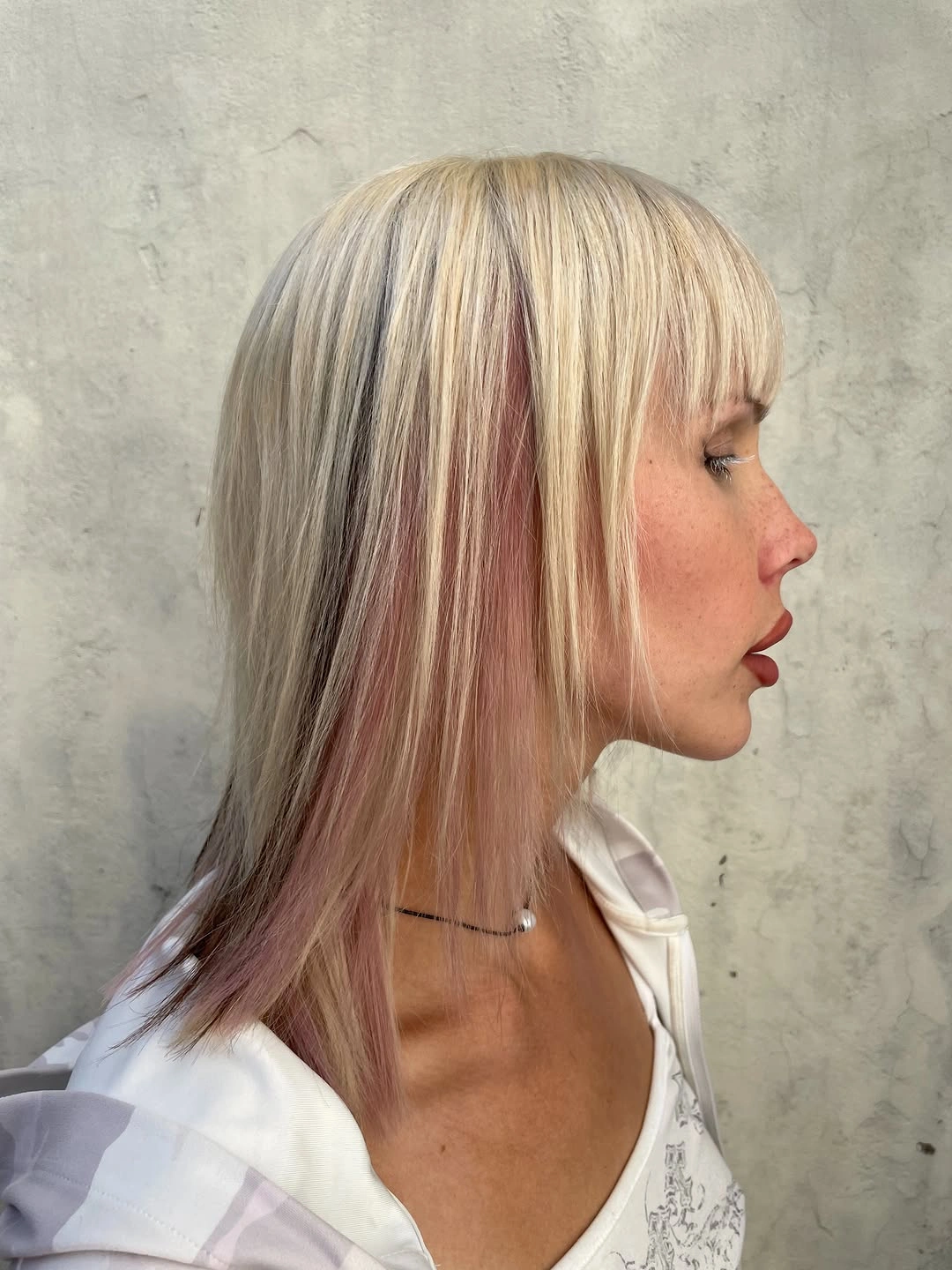 Shoulder-length blonde hair with fringe and rose-pink side panels