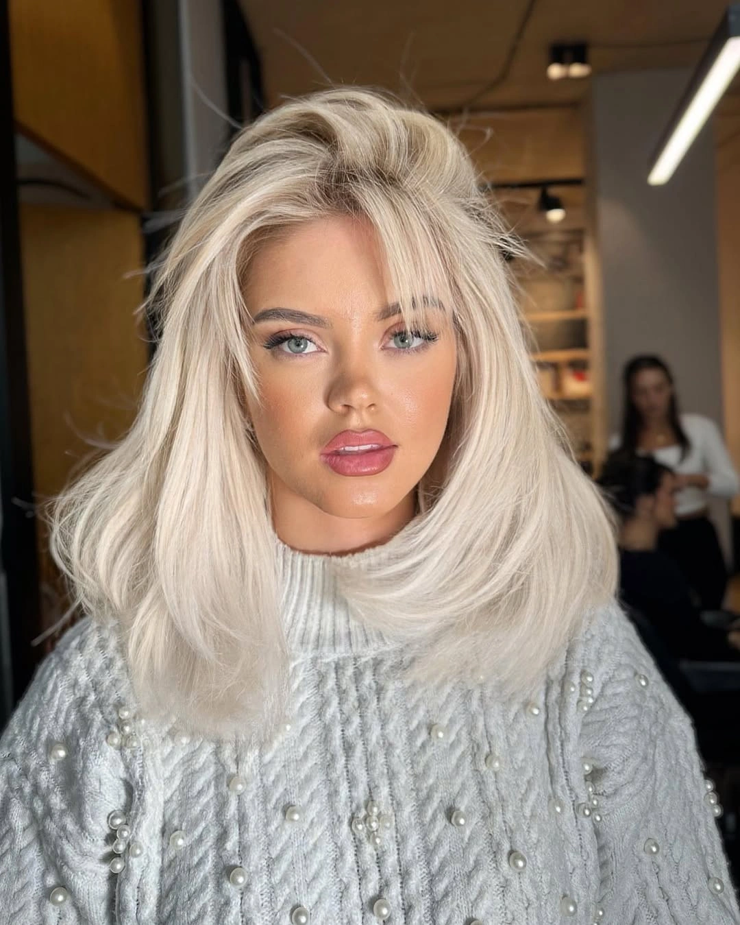 Shoulder-length creamy blonde hair with lifted blowout volume