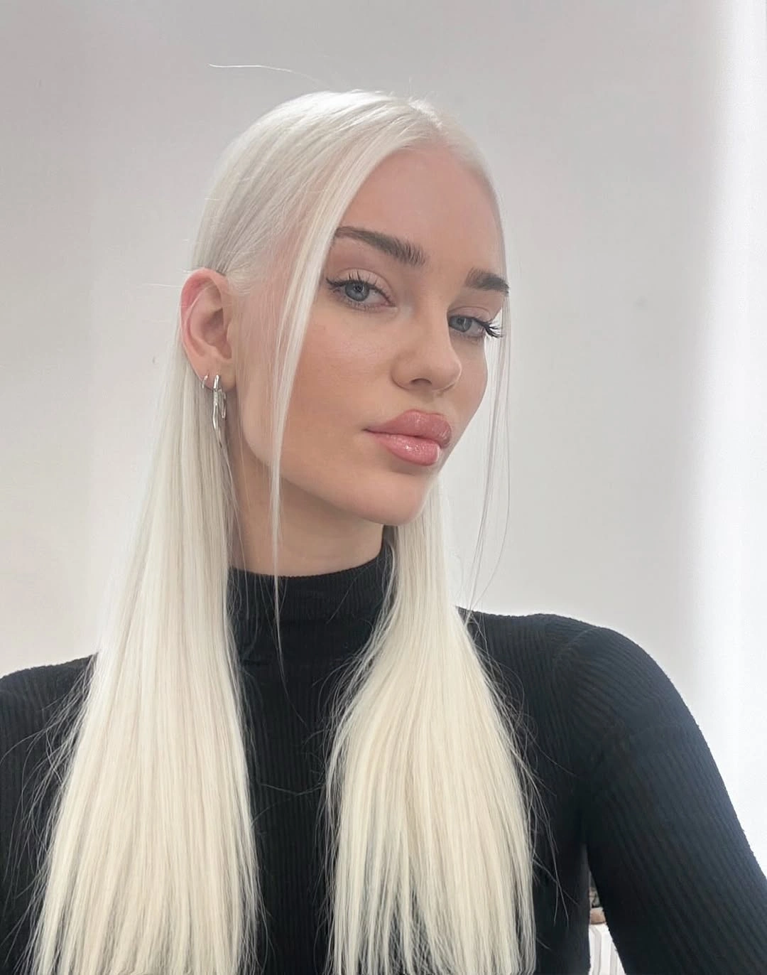 Very pale center-part blonde hair worn straight and sleek