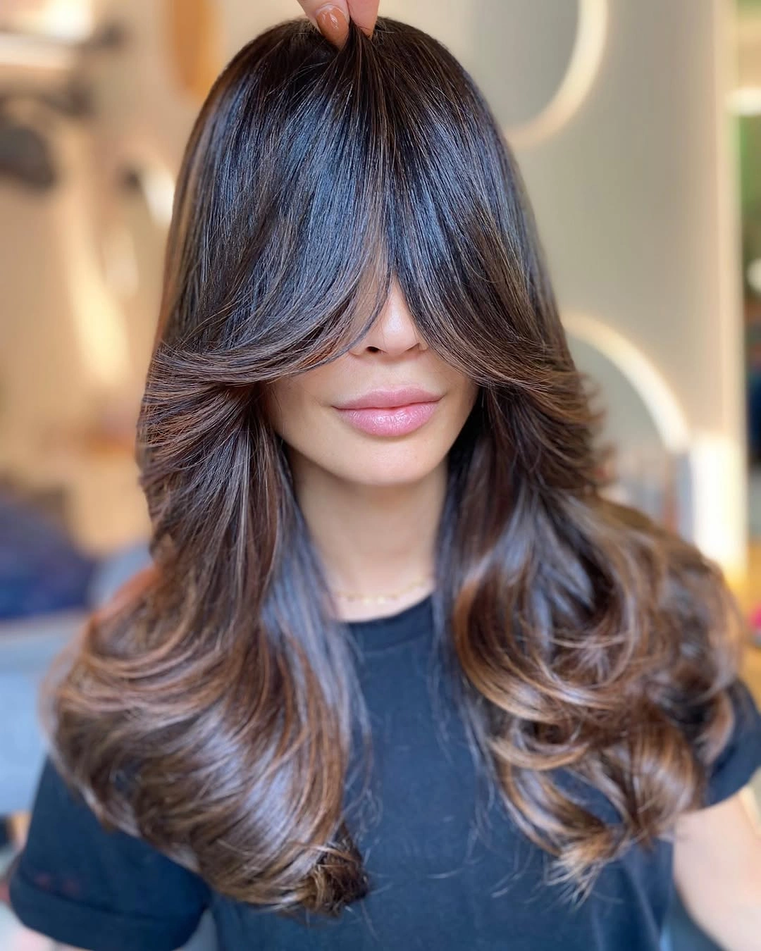 Long brunette layers with curtain bangs and caramel face-framing pieces