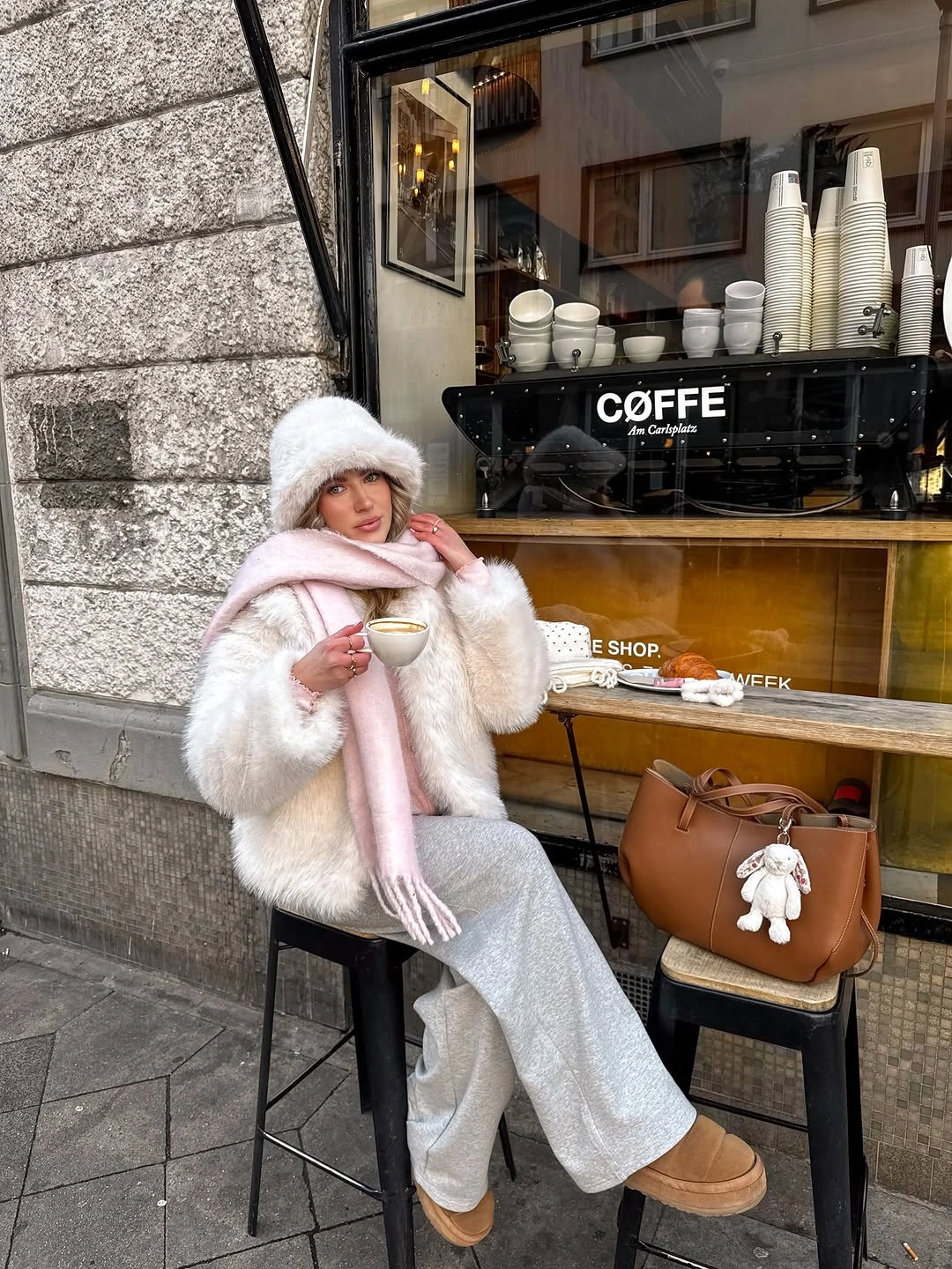 White fluffy jacket pink scarf gray trousers and tan boots