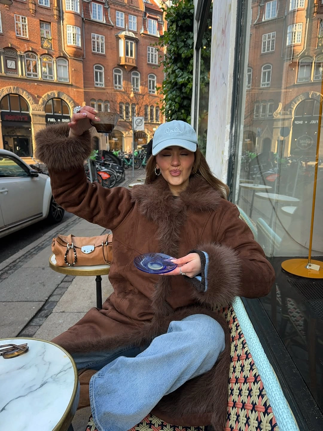 Brown coat with dark trim light blue cap and wide jeans