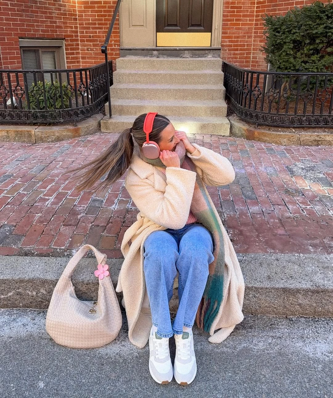Cream textured coat, blue jeans, striped scarf, sneakers, earmuffs