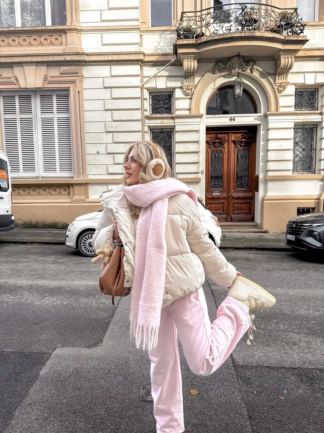 Cream puffer, pink trousers and scarf, light boots, earmuffs, taupe bag