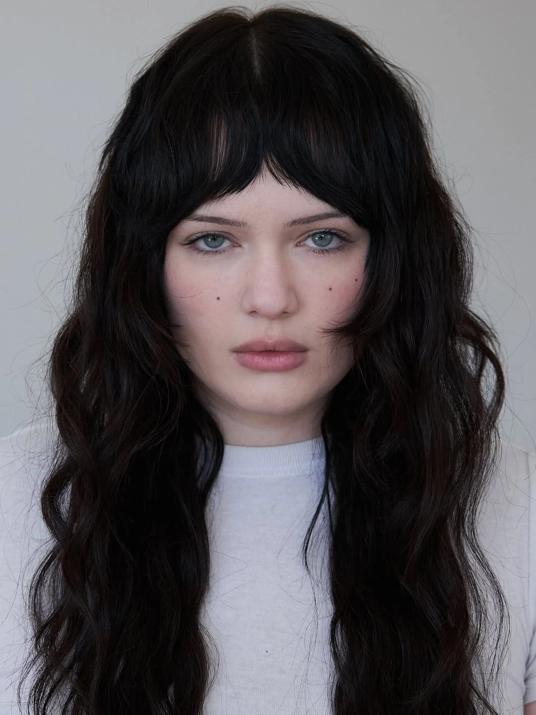 Dark wavy shag haircut with short curved bangs