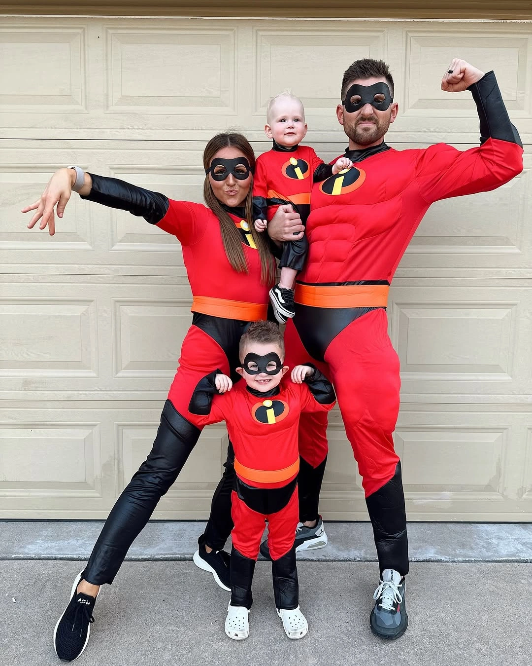 Family in red and black superhero costumes with baby