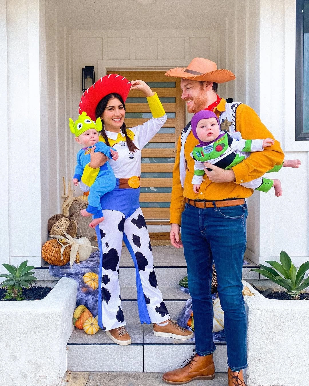 Parents in western costumes holding dinosaur and space-ranger babies