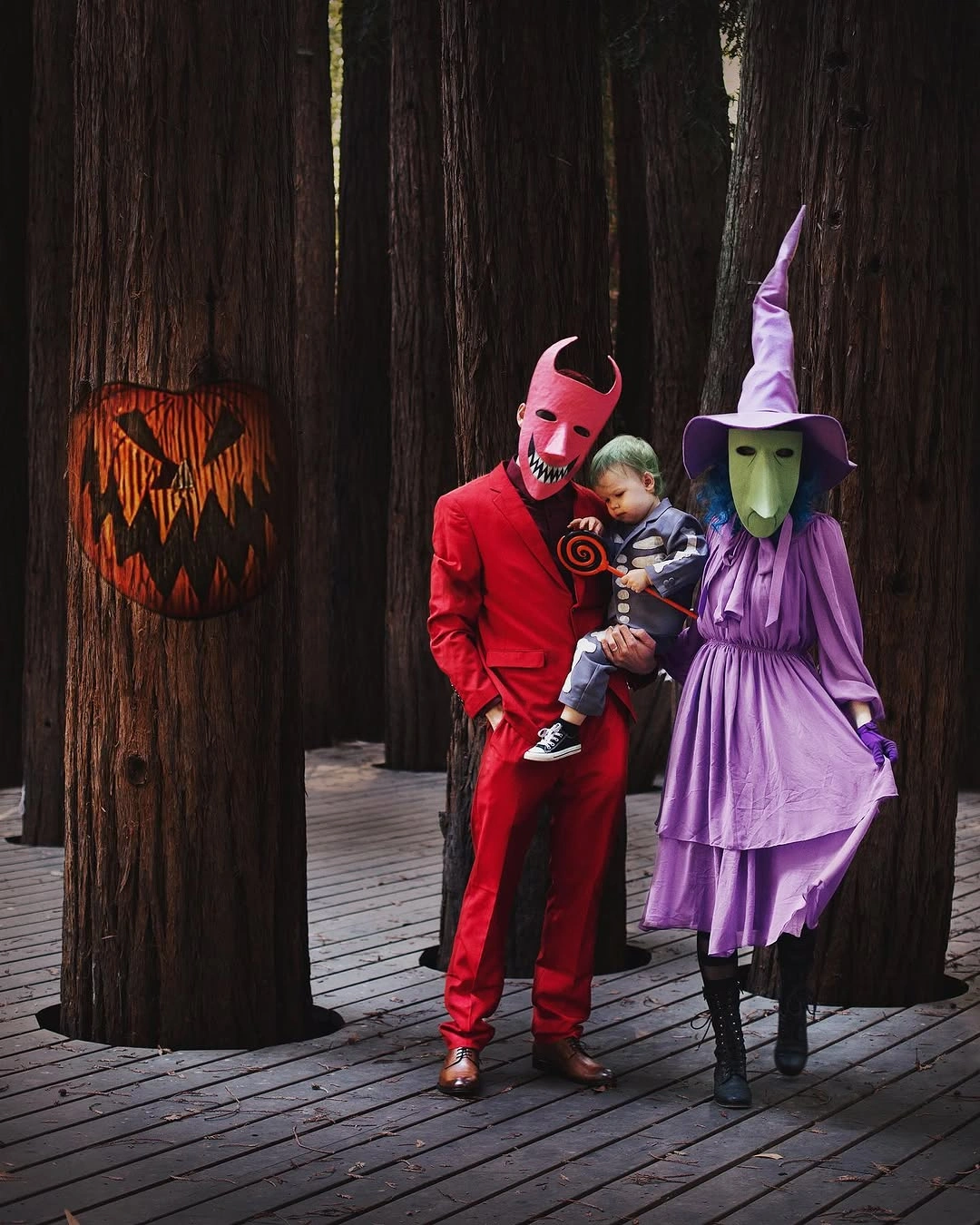 Adults in pink and purple witch costumes holding baby