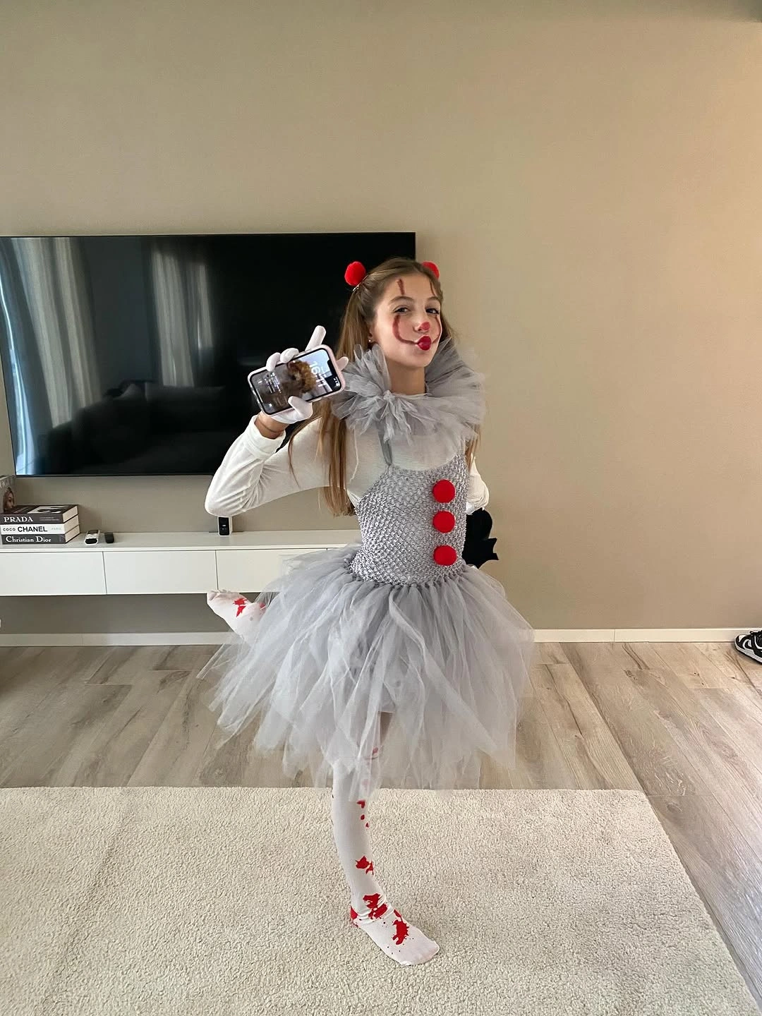 Girl in white ruffled clown dress with red pom-poms