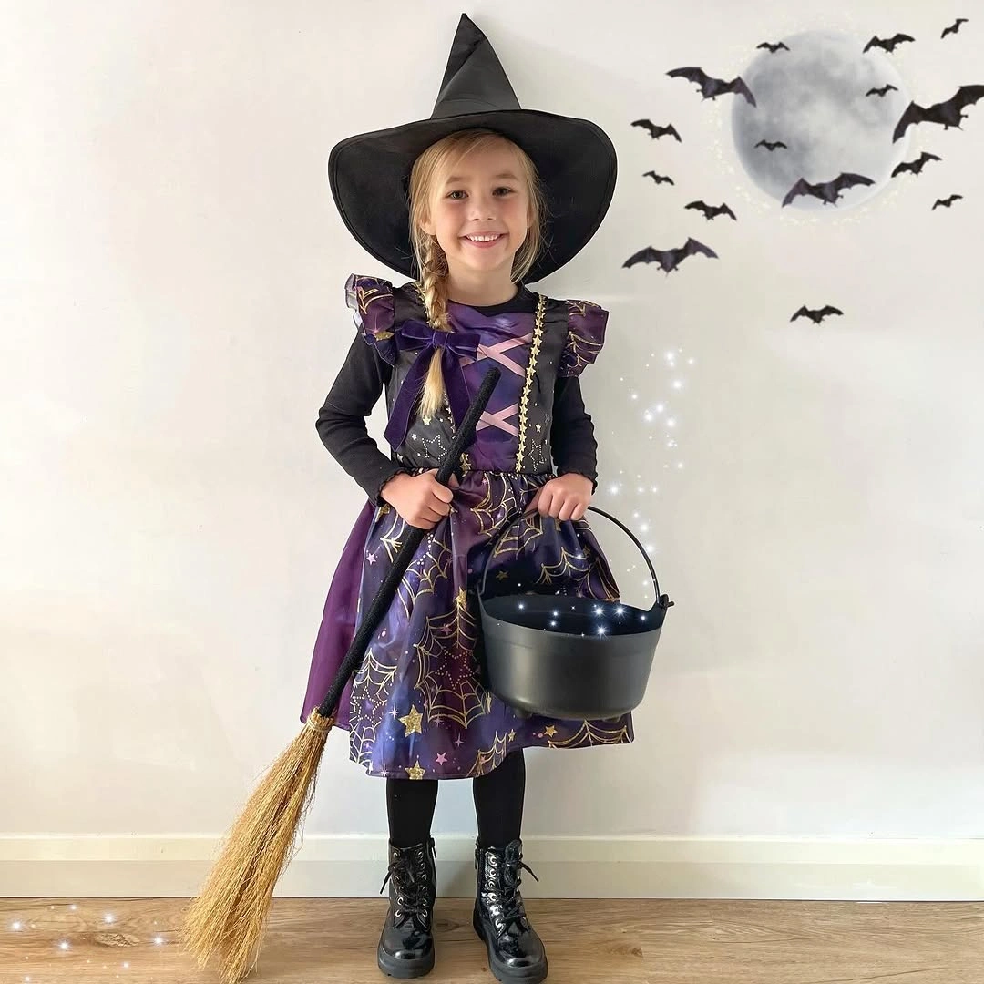 Young girl in purple witch dress with hat broom and bucket