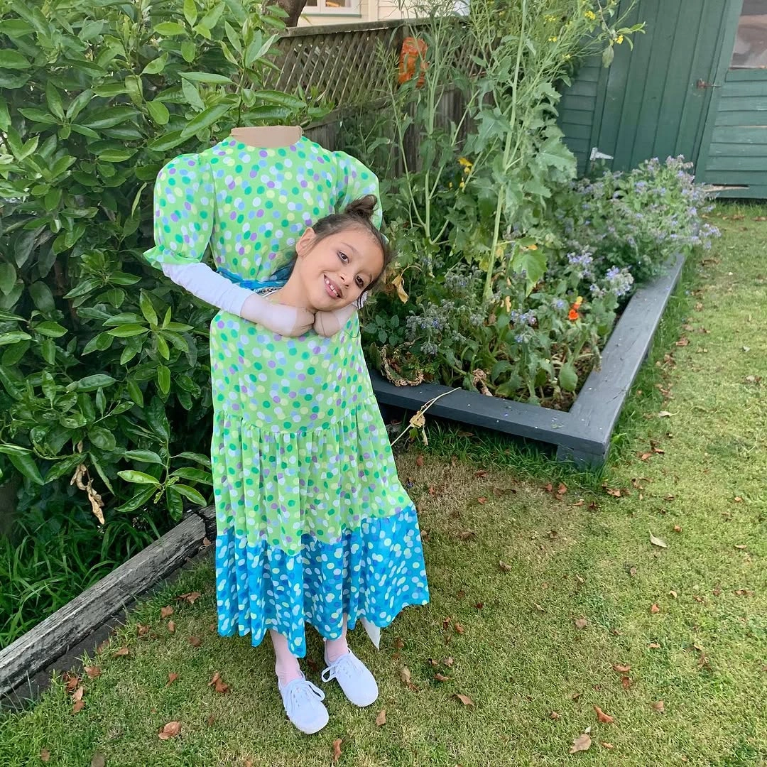 Girl in green blue patterned dress with oversized green bonnet