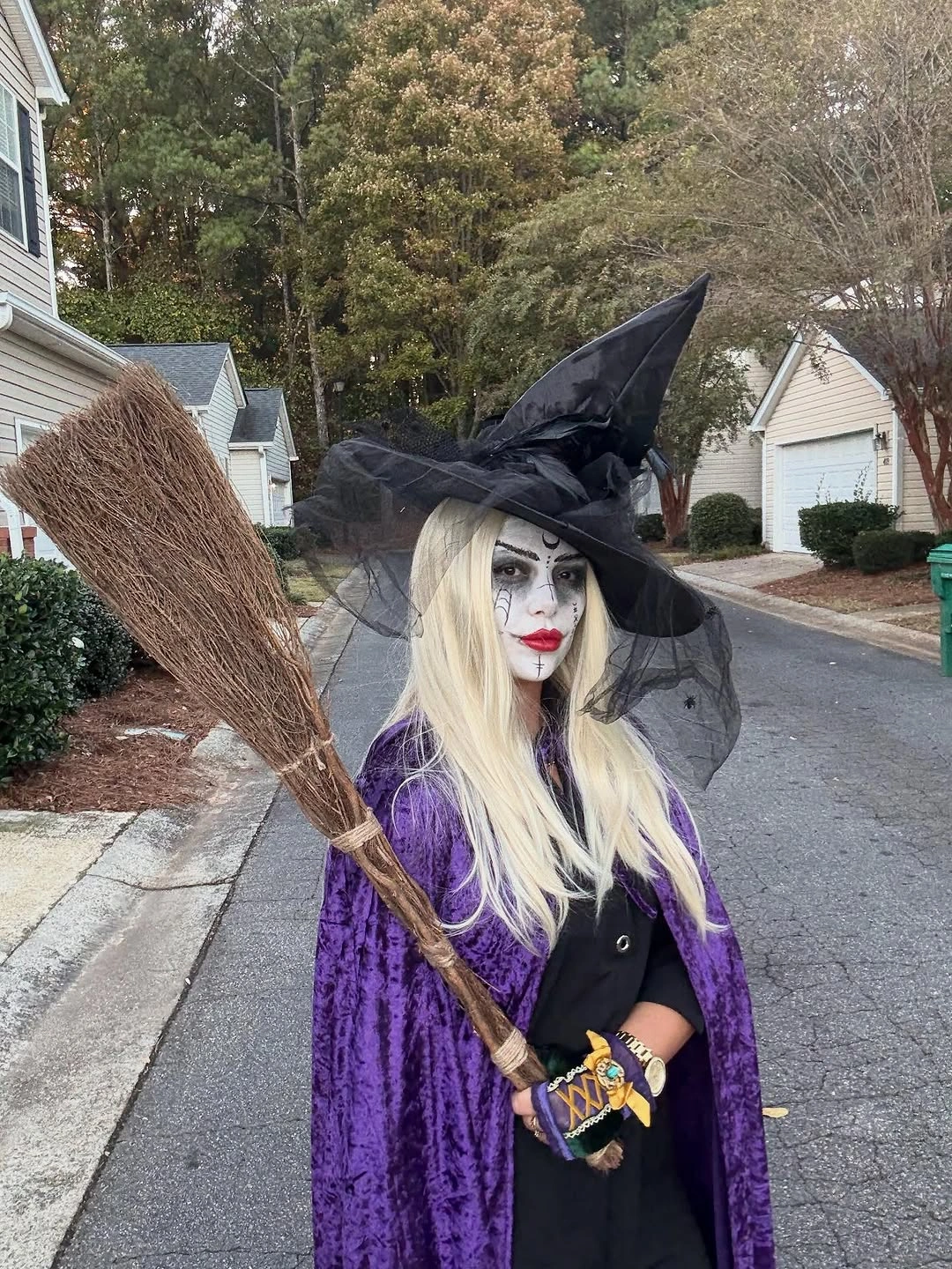 Girl in purple witch cape black hat and pale wig