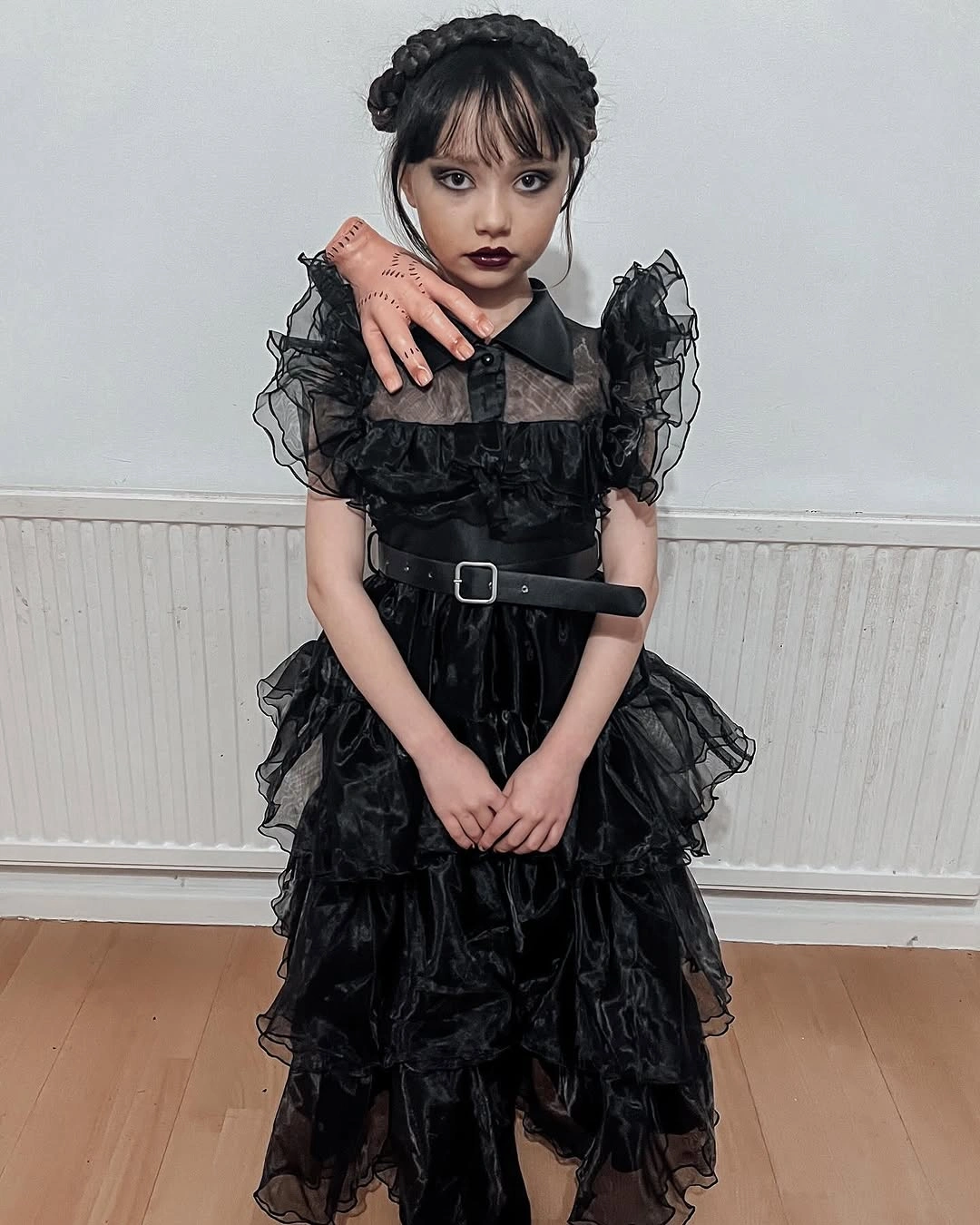 Girl in black layered ruffle dress with belt and bows