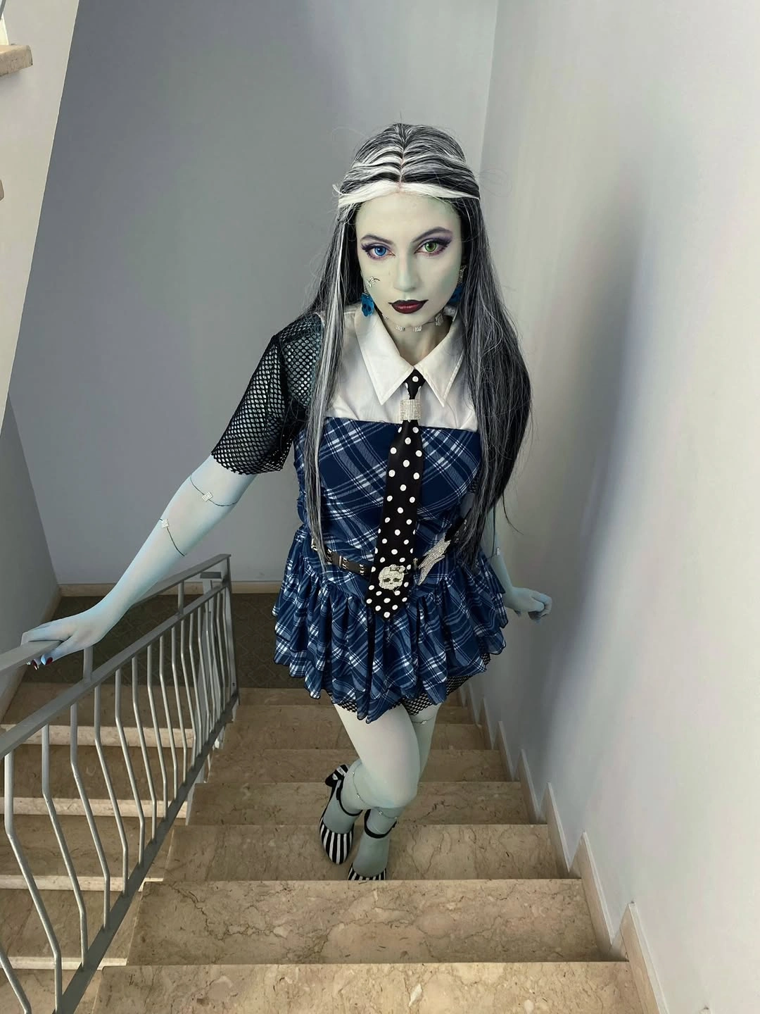 Girl in pale makeup striped wig and blue plaid skirt