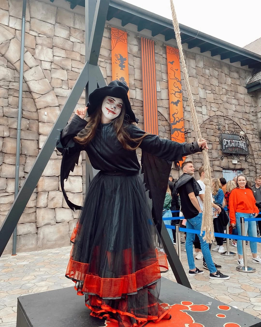 Girl in black witch costume with red trim and cape