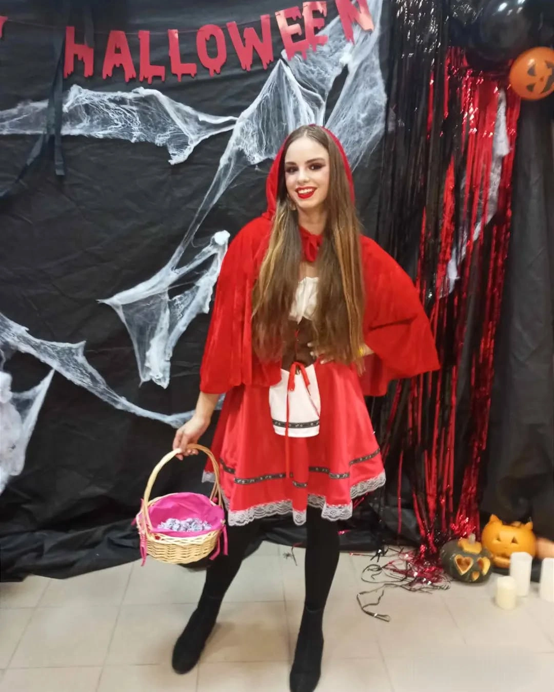 Girl in red hooded cape white dress black tights and boots