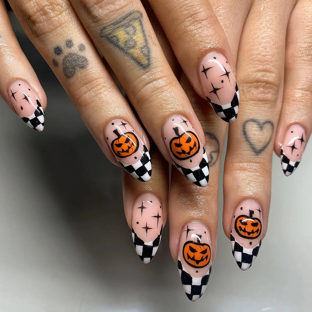 Long nude nails with checkerboard tips and orange jack-o-lantern faces