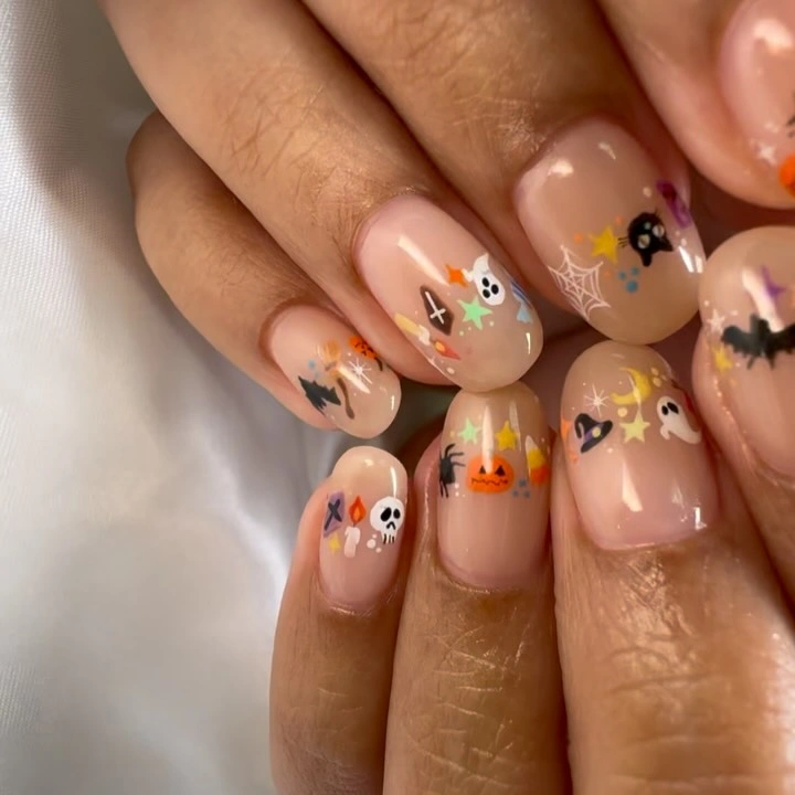 Short nude nails with tiny pumpkins ghosts cats and stars