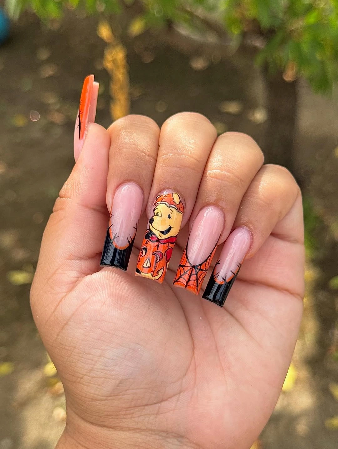 Long nude nails with orange pumpkin character and dark accents