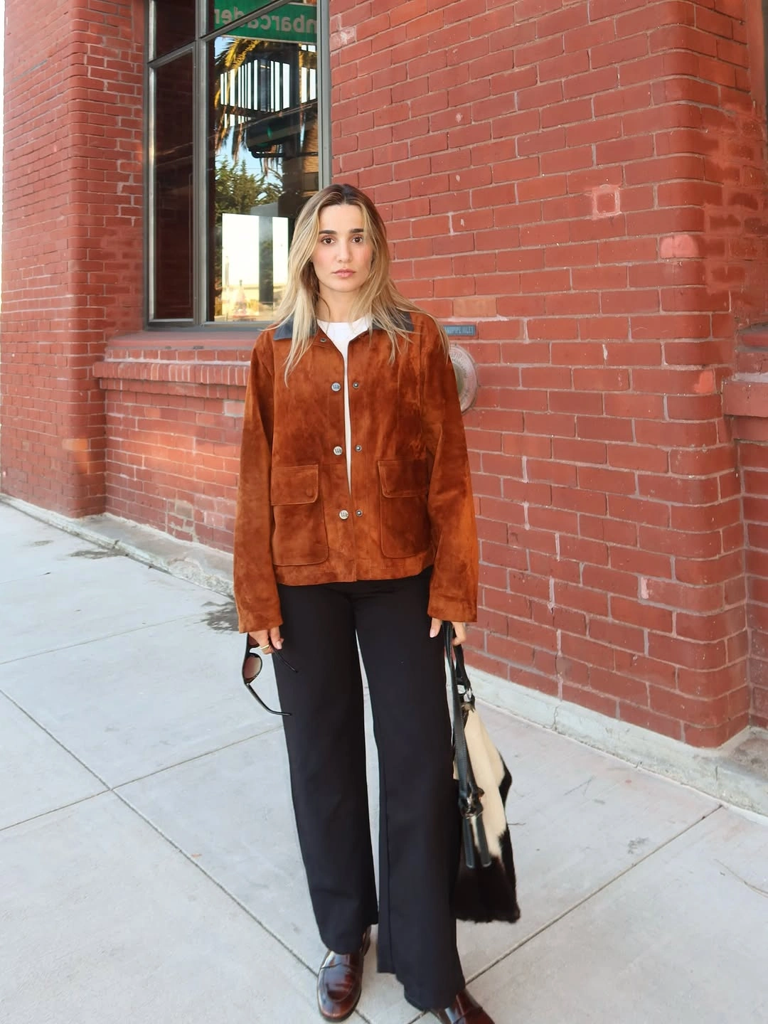 Rust-brown jacket with white trim and black wide trousers