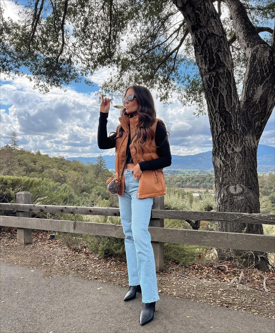 Tan padded-looking vest black top light jeans black ankle boots