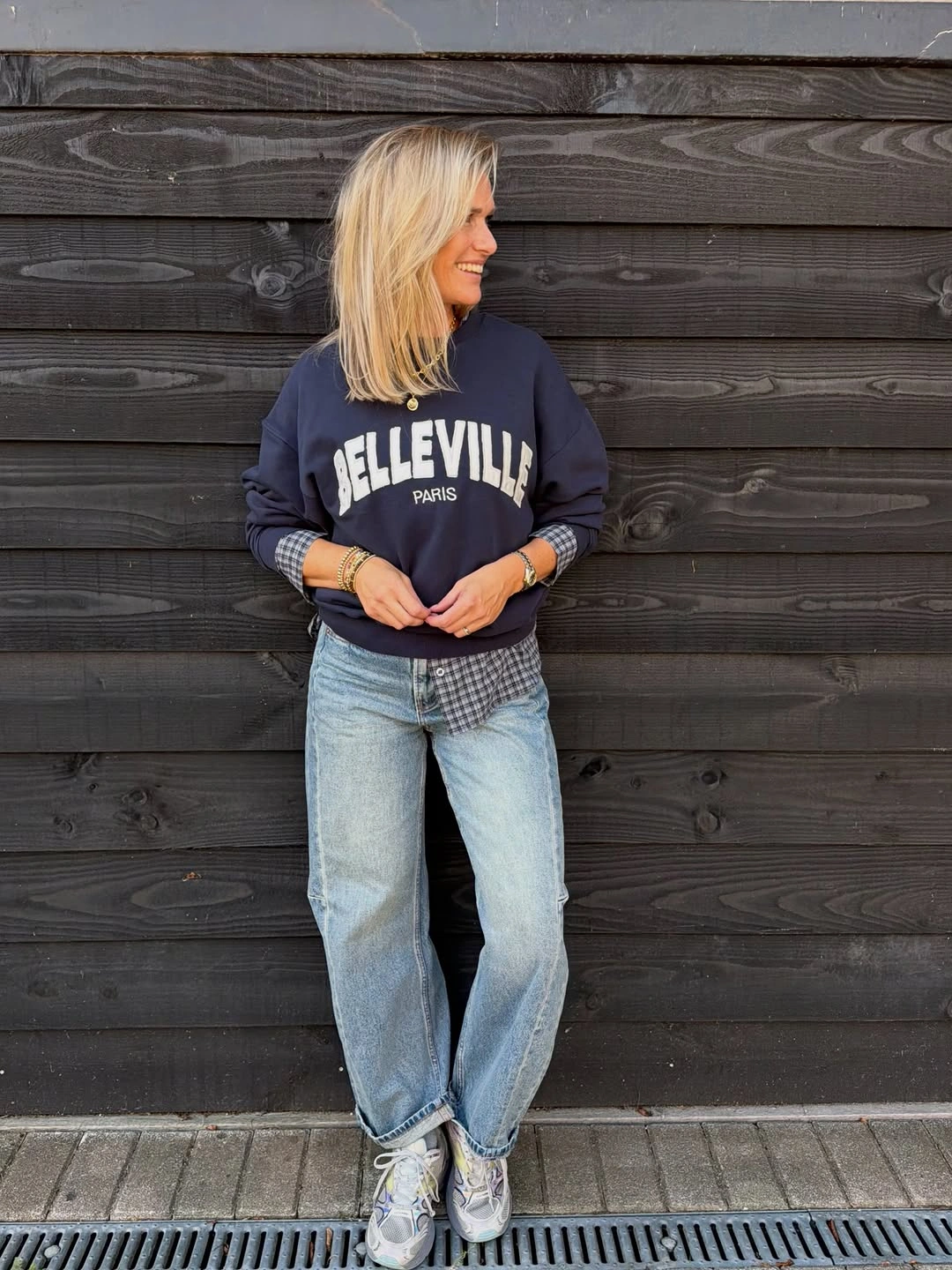 Navy graphic sweatshirt with cuffed jeans and gray sneakers