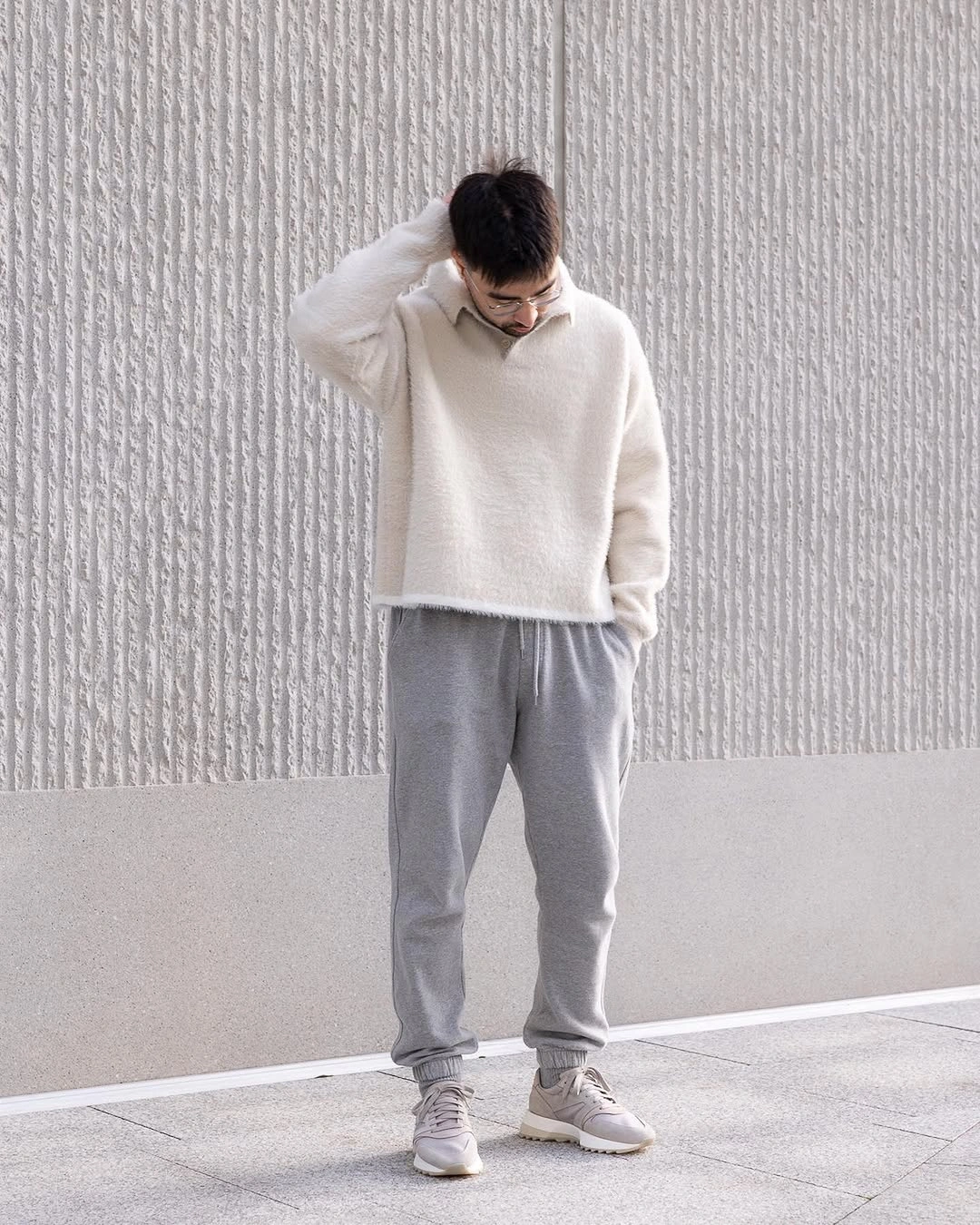 Cream knit sweater with relaxed gray trousers and white sneakers