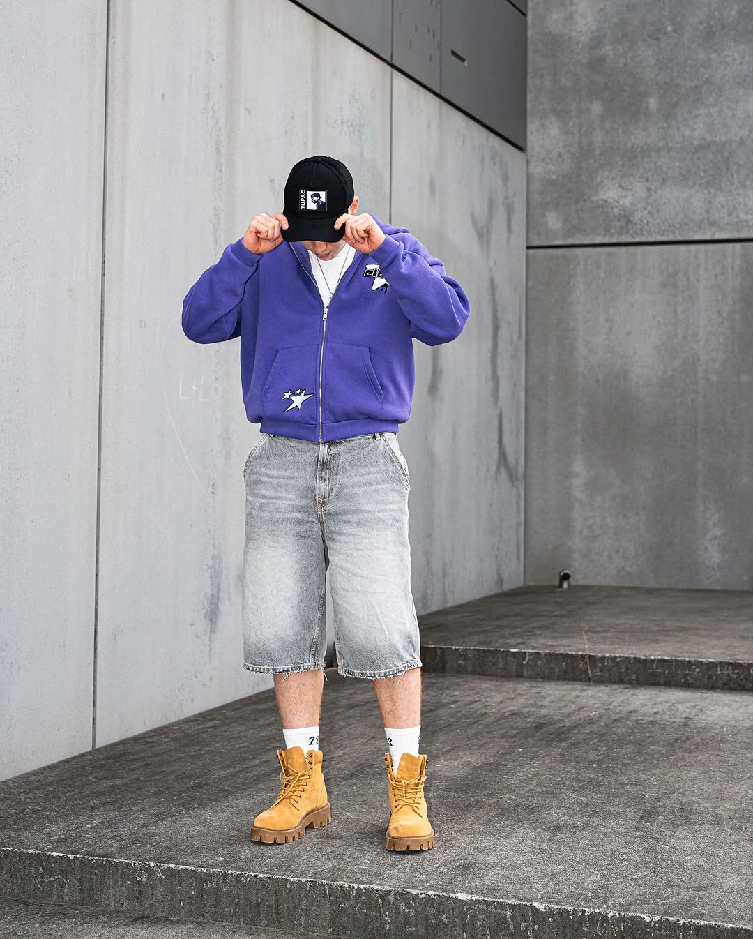 Purple zip jacket with faded denim long shorts and tan boots
