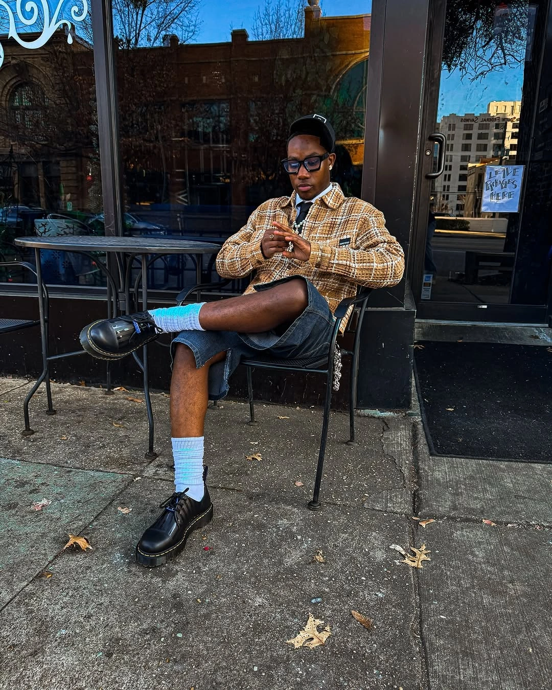 Brown plaid overshirt with black shorts, white socks, and black shoes