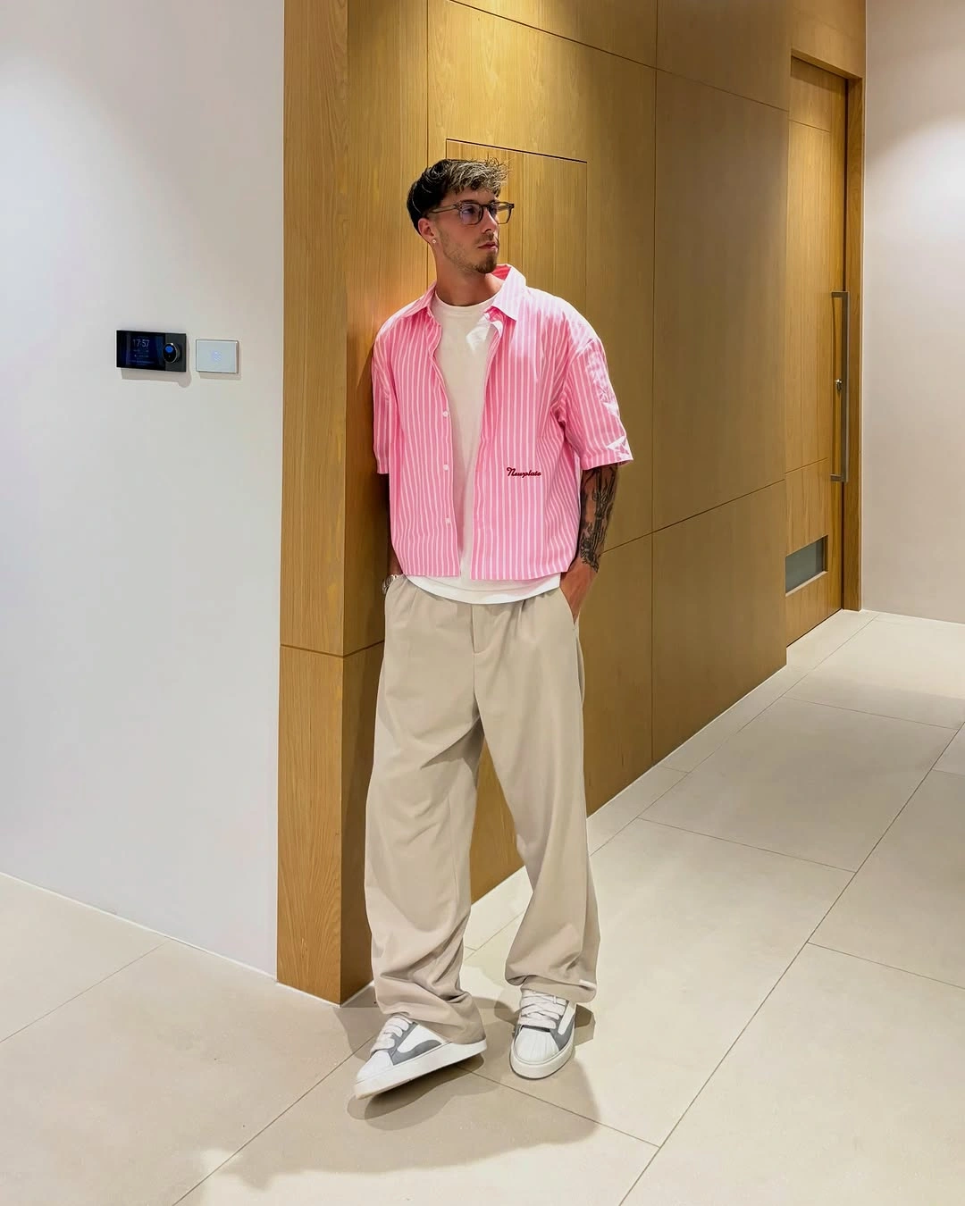 Pink striped shirt layered over white tee and cream trousers